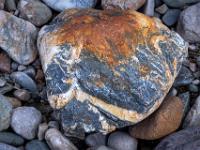 Grauer Stein mit weißlicher Maserung und rostfarbenem Fleck